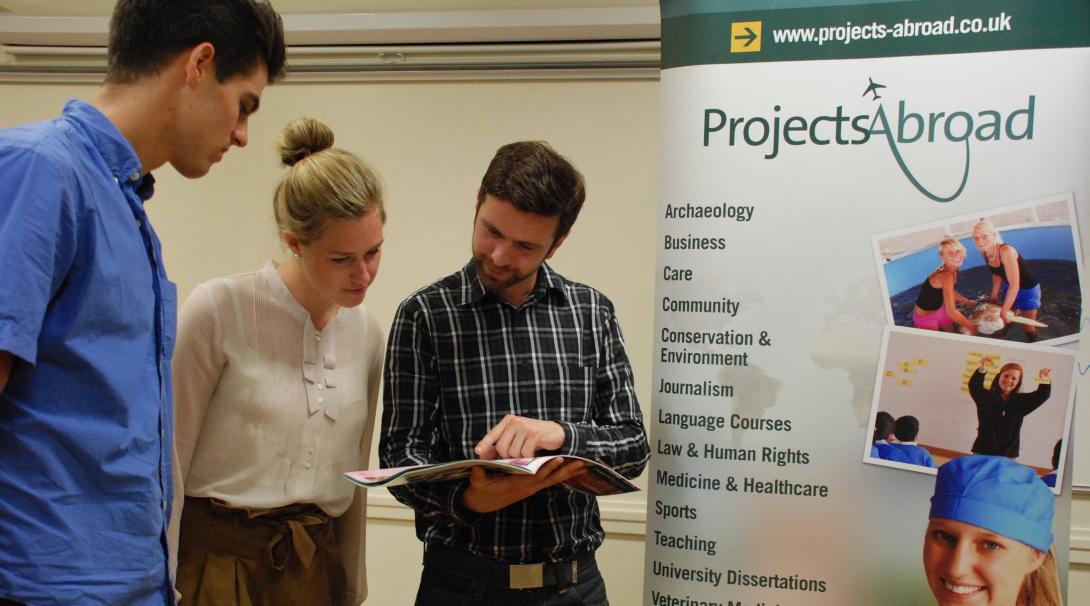 Estudiantes en un evento preguntando por más información. Personal de Projects Abroad informando a estudiantes sobre nuestros proyectos.